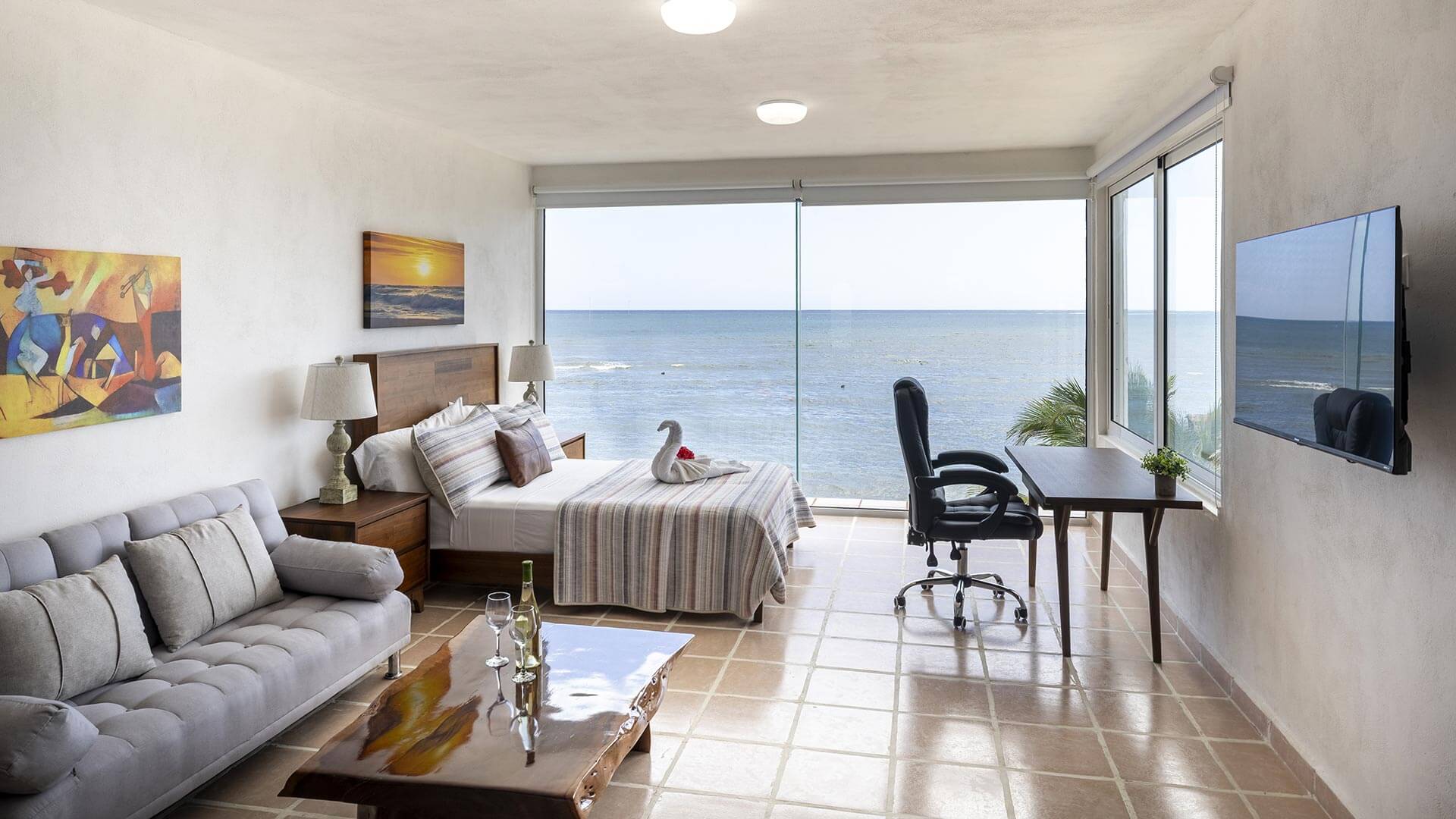 Studio spacieux et lumineux offrant une vue panoramique sur la mer, avec lit King, coin salon, espace de travail et grandes fenêtres du sol au plafond.